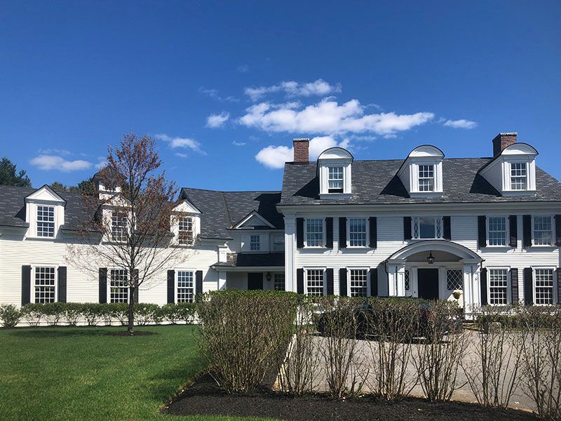 A large white house with a gray roof and black shutters