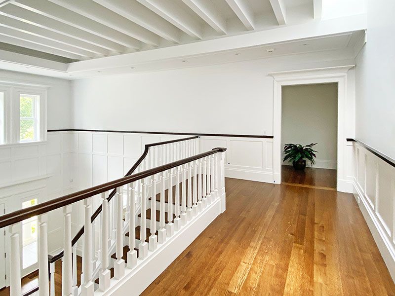 A hallway with wooden floors and stairs in a house.