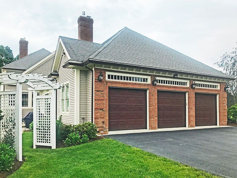A large house with three garage doors and a driveway.