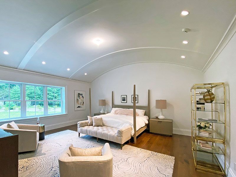 A bedroom with a four poster bed , two chairs , a couch and a shelf.