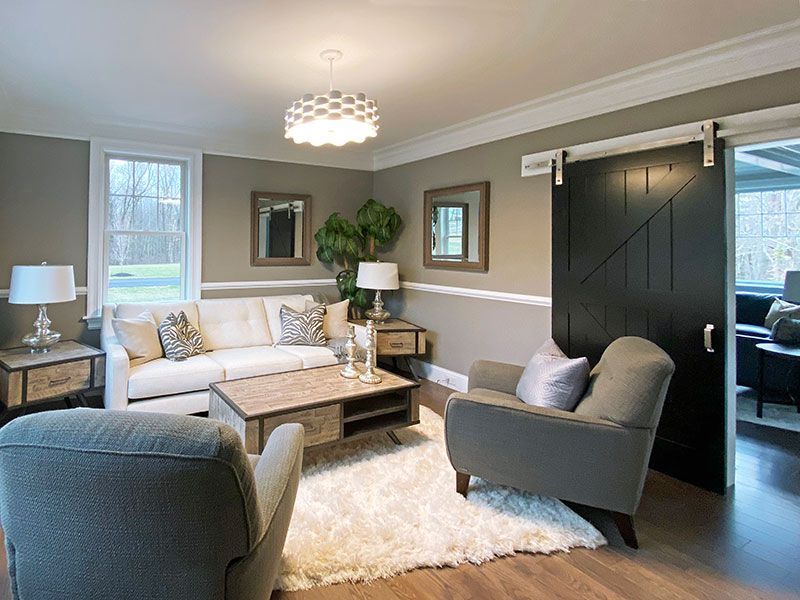 A living room with a couch , chairs , coffee table and sliding barn door.