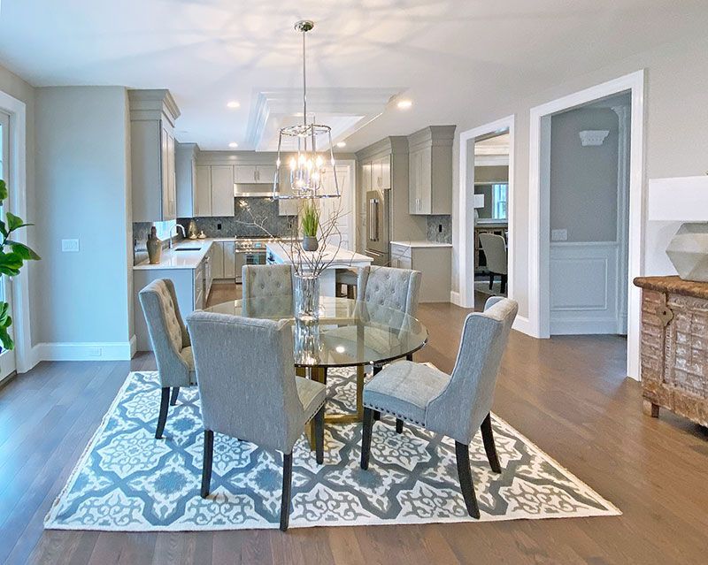 A dining room with a round table and chairs and a rug.