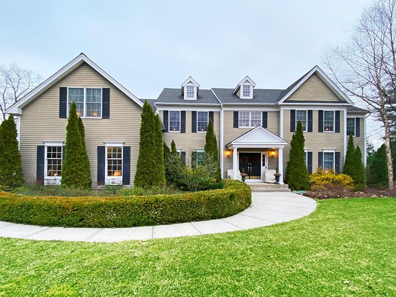 A large house with black shutters and a lush green lawn
