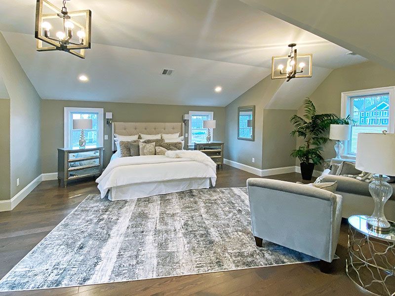 A bedroom with a large bed , chairs , lamps and a rug.