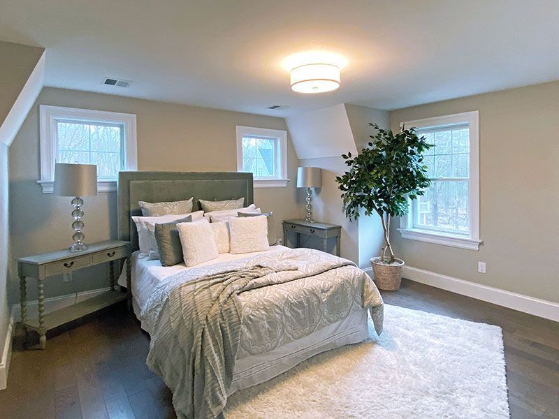 A bedroom with a bed , nightstands , lamps and a plant.