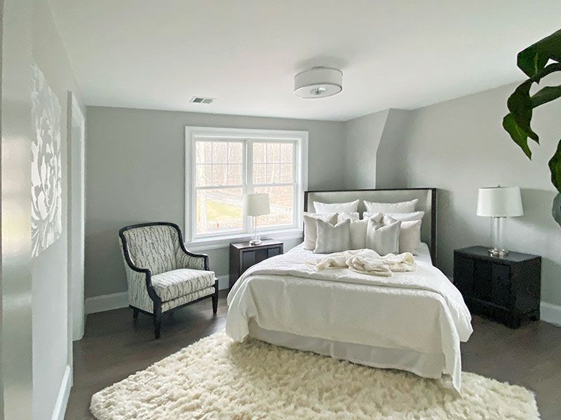A bedroom with a bed , chair , nightstand and rug.