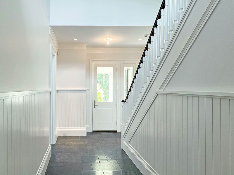 A hallway with white walls and a staircase in a house