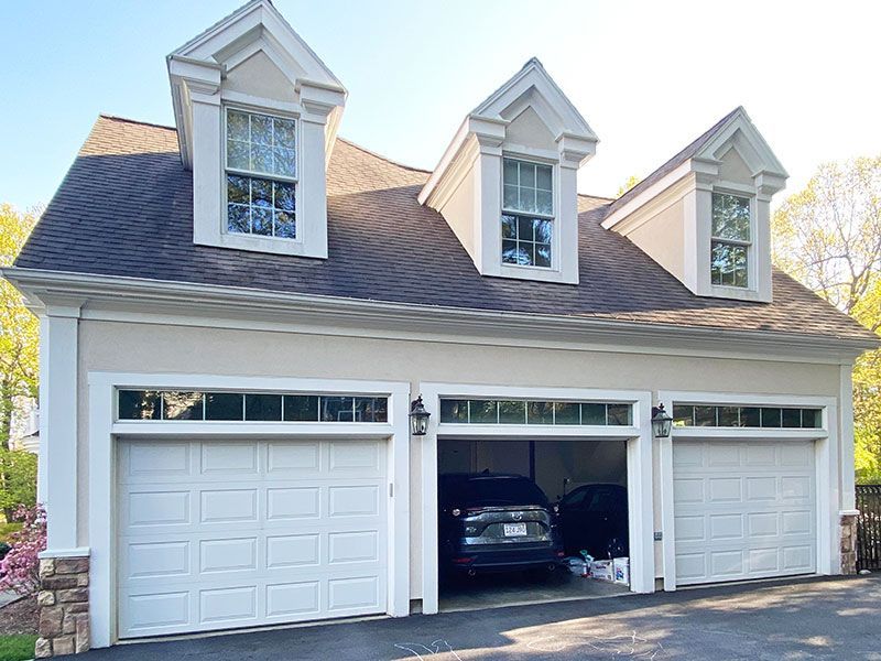 A car is parked in a garage with the doors open.