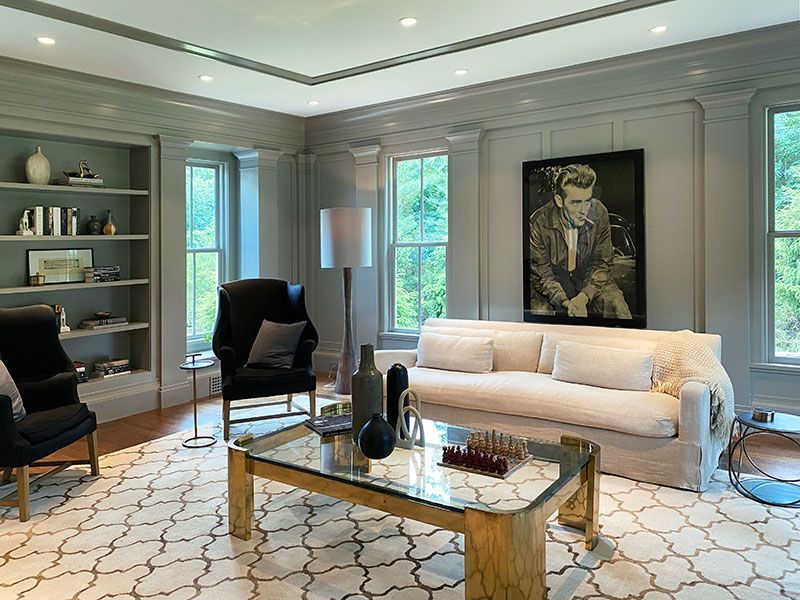 A living room with a couch , chairs , a coffee table and a painting on the wall.