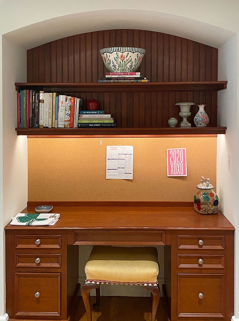 A wooden desk with a cork board and a shelf above it.