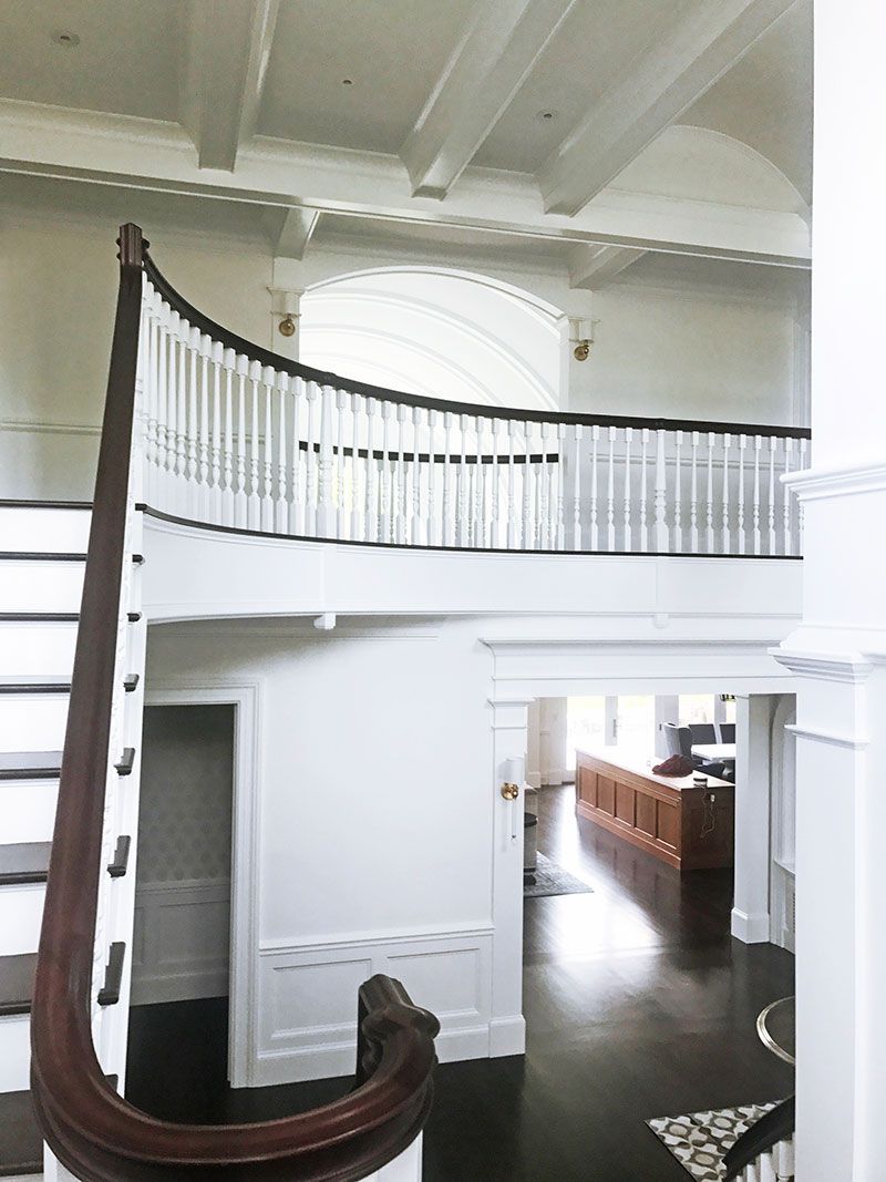 A large white house with a curved staircase and a balcony.