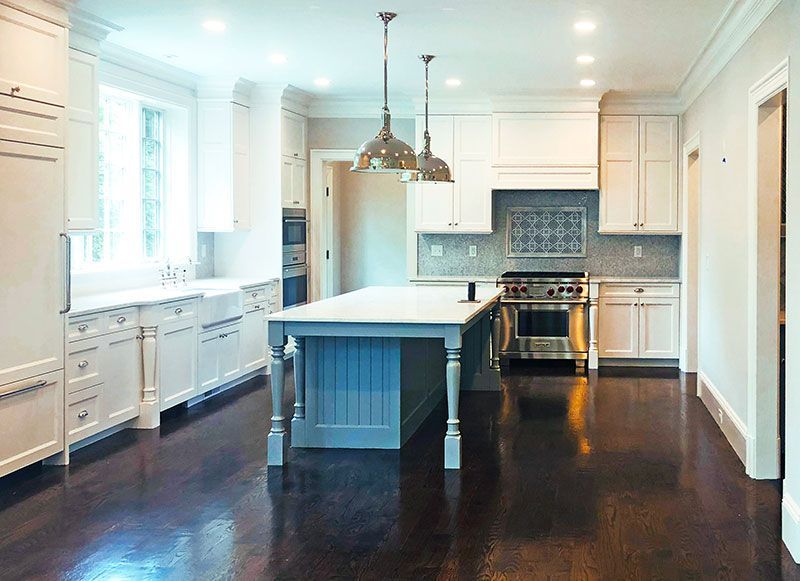 A kitchen with white cabinets and a large island in the middle.