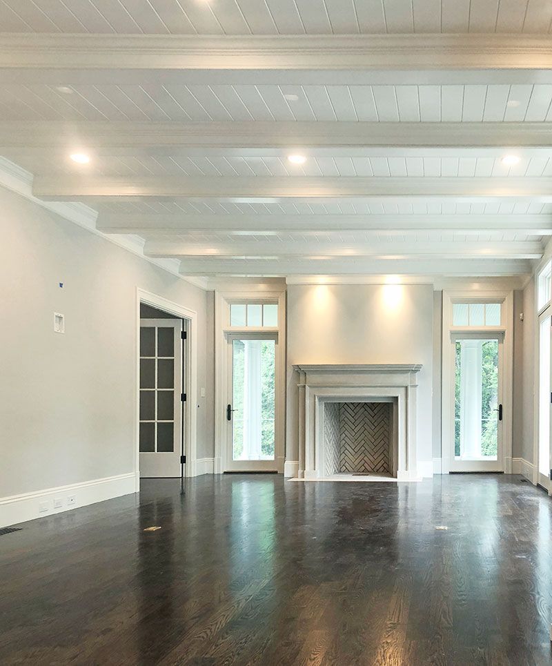 An empty living room with a fireplace and lots of windows