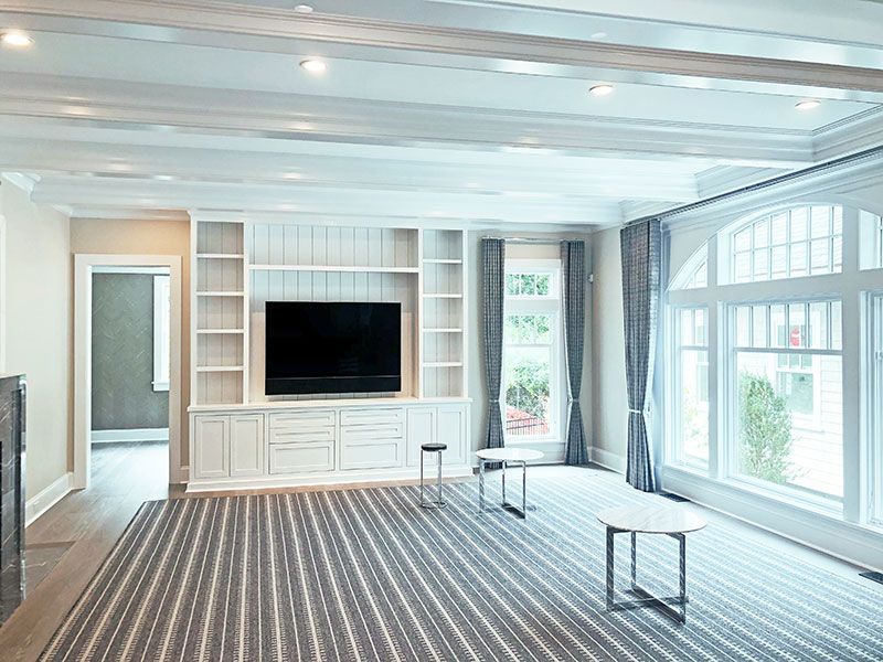 A living room with a flat screen tv on the wall and a striped rug.