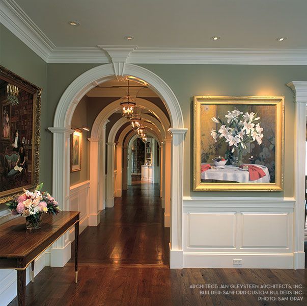 A long hallway with arches and a painting on the wall