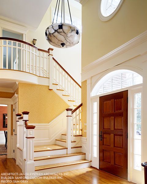 A staircase in a house with a chandelier hanging from the ceiling