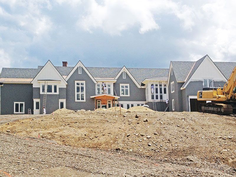 A large house is being built on top of a dirt field