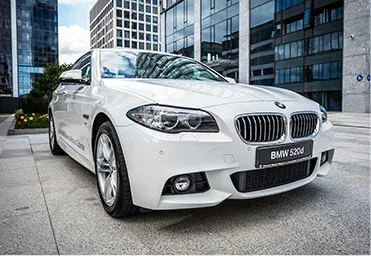 White BMW 520d parked in front of modern office building.