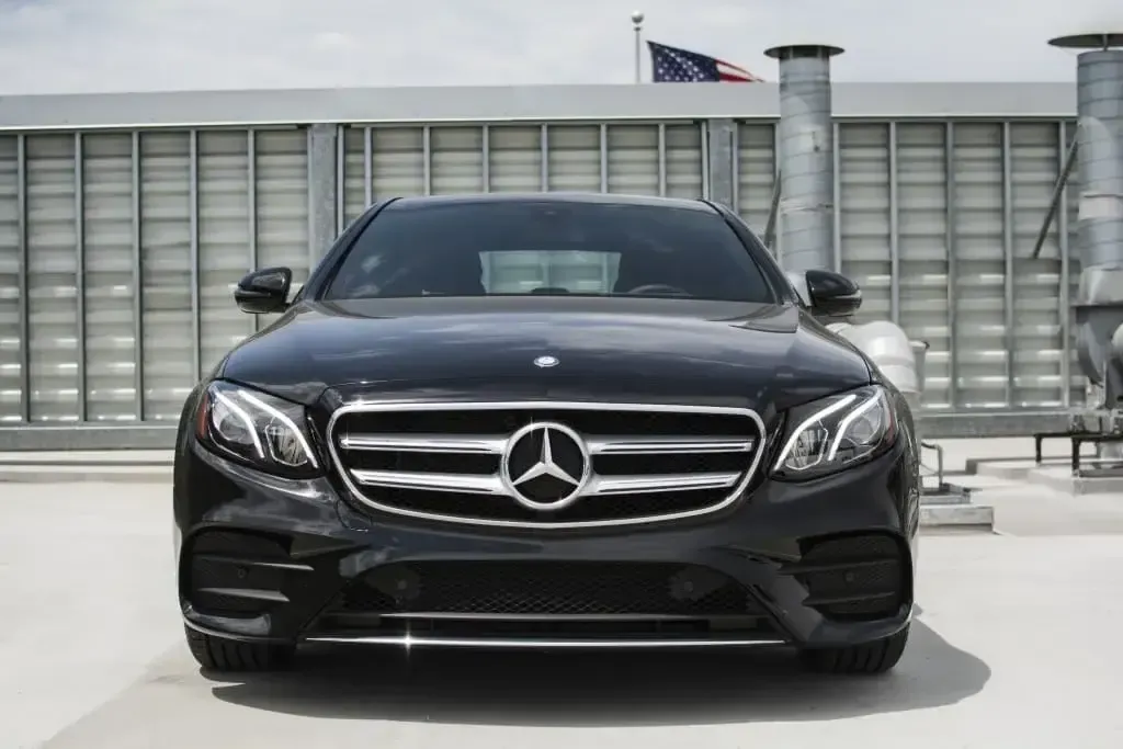 Black Mercedes-Benz sedan parked on a rooftop. American flag and industrial ventilation visible in the background.