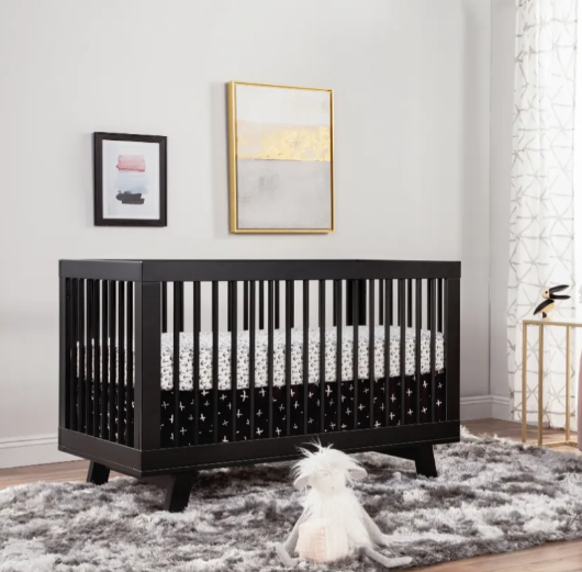 Black crib with white and black bedding in a modern nursery.