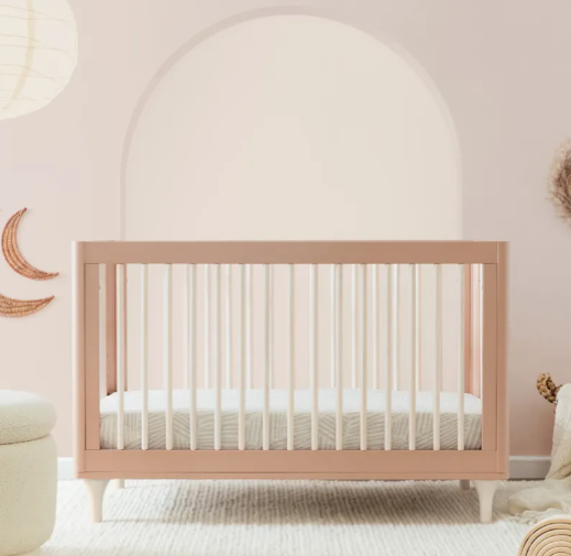 Pink crib with white slats in a nursery.
