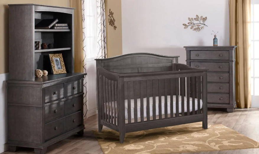 Gray nursery furniture set: crib, bookcase, dresser, and chest of drawers.