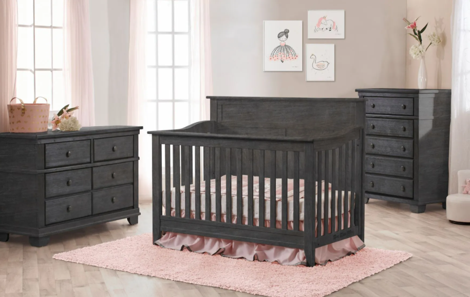 Gray nursery furniture set including a crib, dresser, and chest of drawers. Pink rug and bedding.