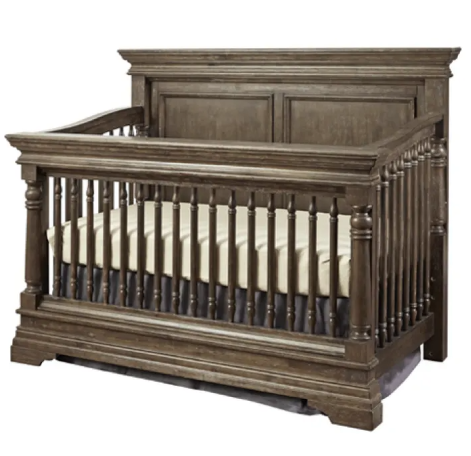 Brown wooden crib with a mattress and decorative posts.