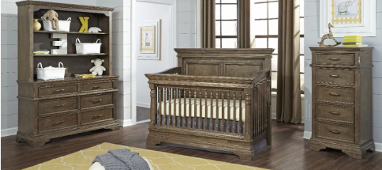 A nursery set with a crib, dresser with hutch, and tall chest, all in a weathered wood finish.