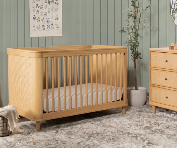 Wooden crib with cane sides in a nursery setting.