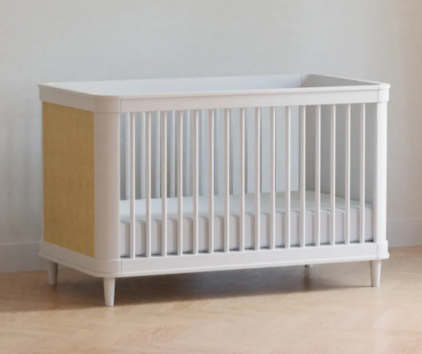White and yellow baby crib on a light wood floor.