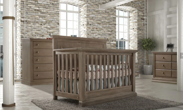 Wooden crib and matching furniture set in a neutral-toned nursery.