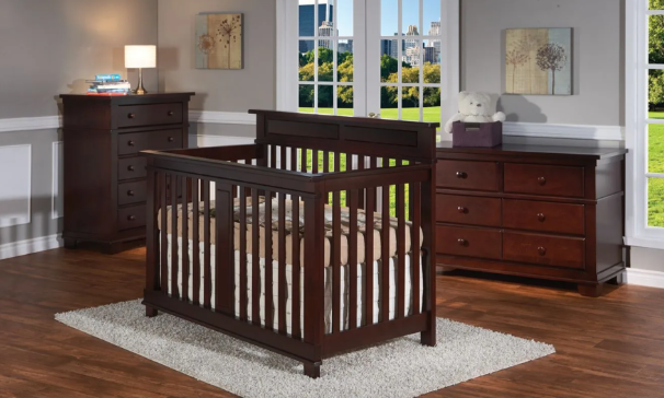 Dark brown nursery furniture set: crib, chest of drawers, dresser, and rug on a hardwood floor.