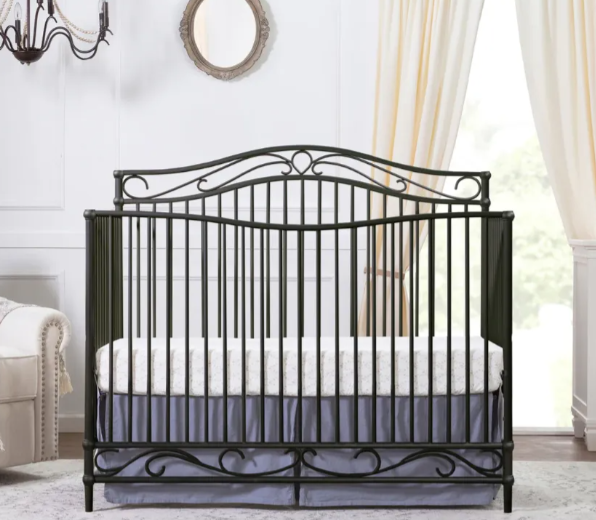 Dark metal crib with curved headboard and footboard, gray bedding.