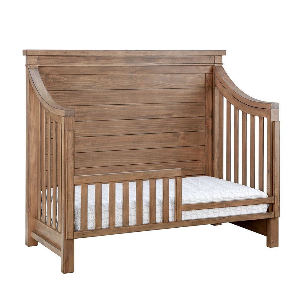 Wooden toddler bed with low side, mattress visible.