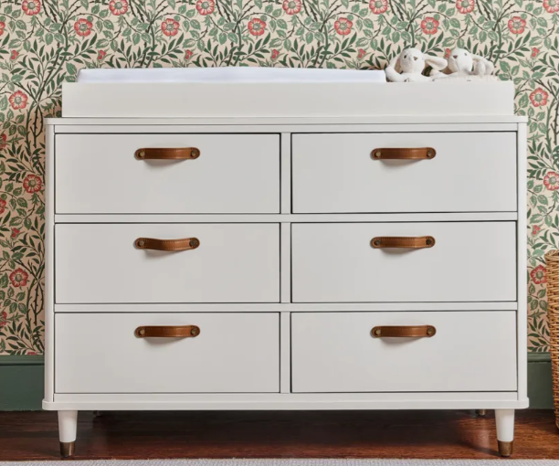 White dresser with leather handles and changing pad.