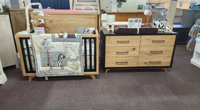 A crib with a zebra design blanket and a matching dresser in a furniture store.