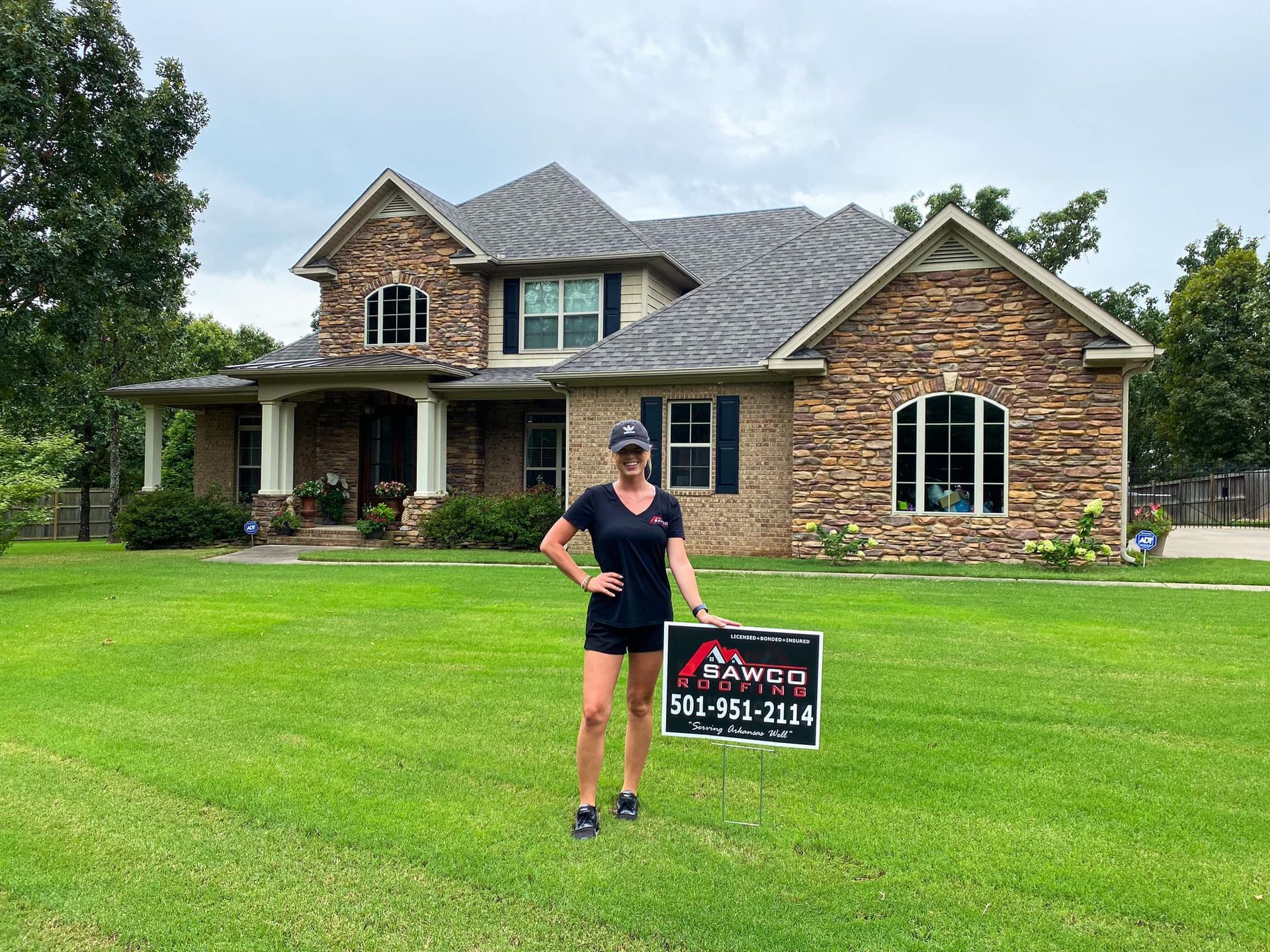 lady with a Sawco Roofing sign in front of a house