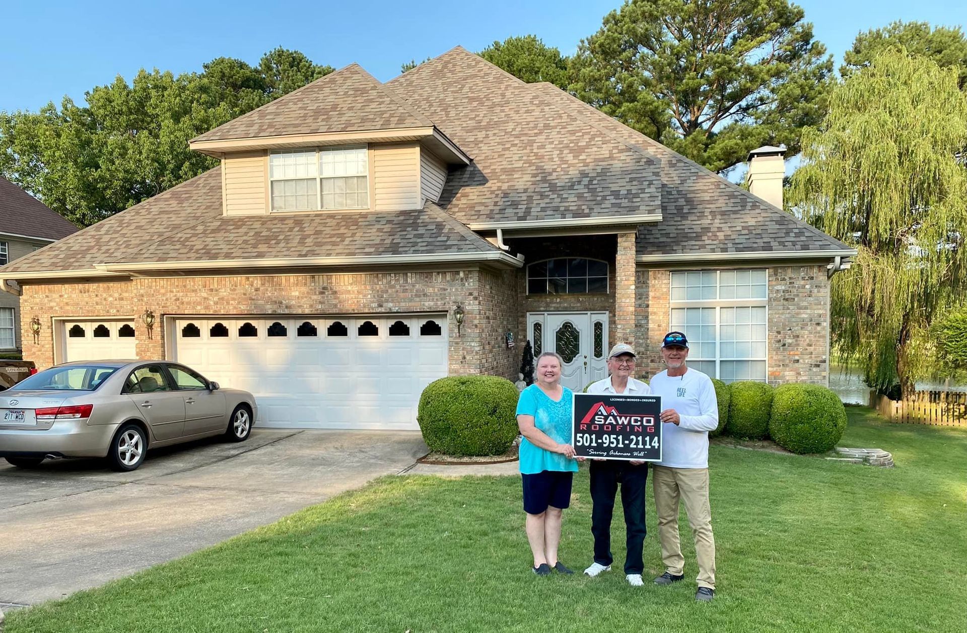 Homeowners holding a Sawco Roofing sign