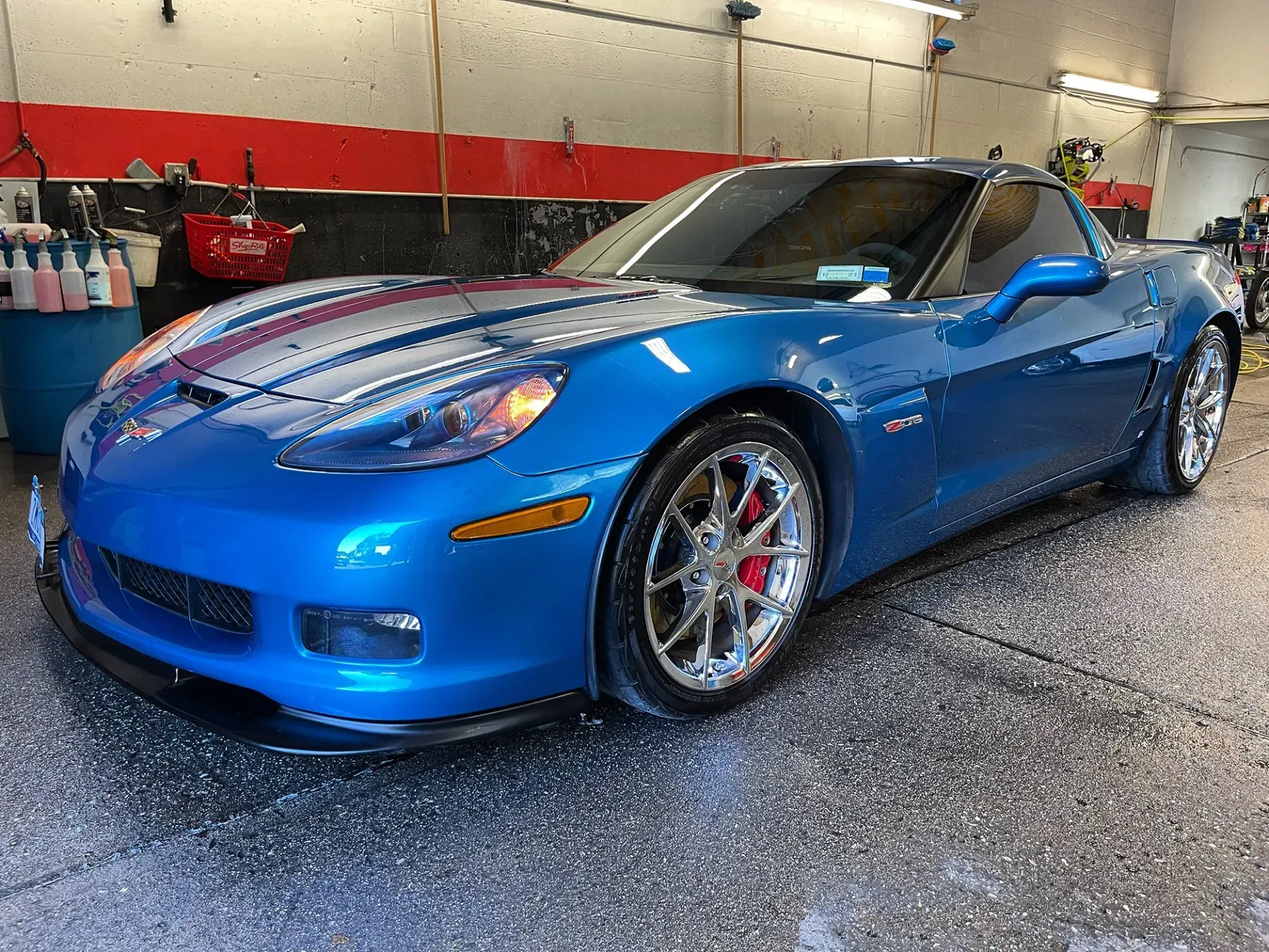 Blue Corvette sports car being washed in a car wash bay.