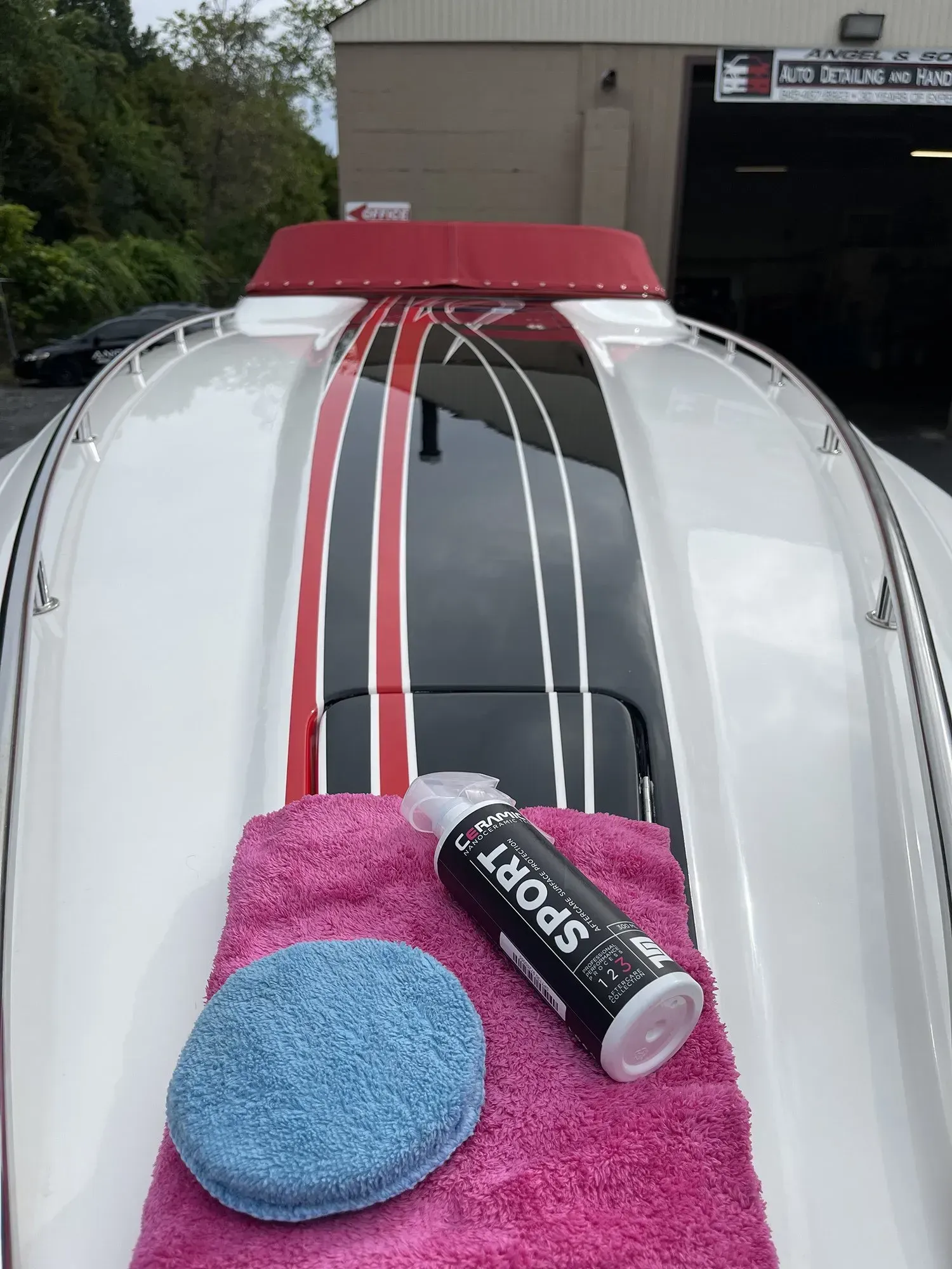 White boat with red, black stripes, cleaning supplies on deck.