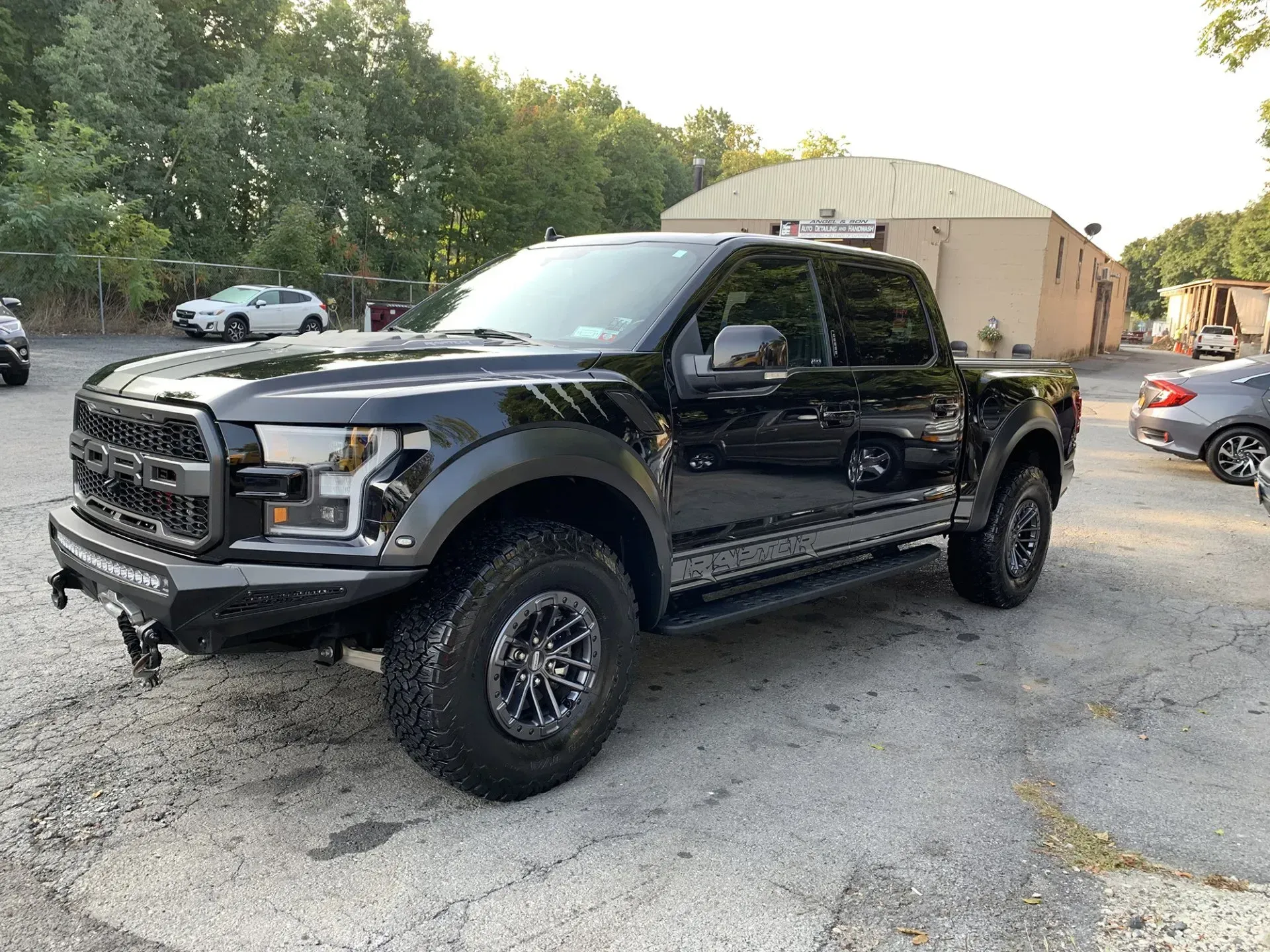 Black Ford Raptor truck parked on asphalt.