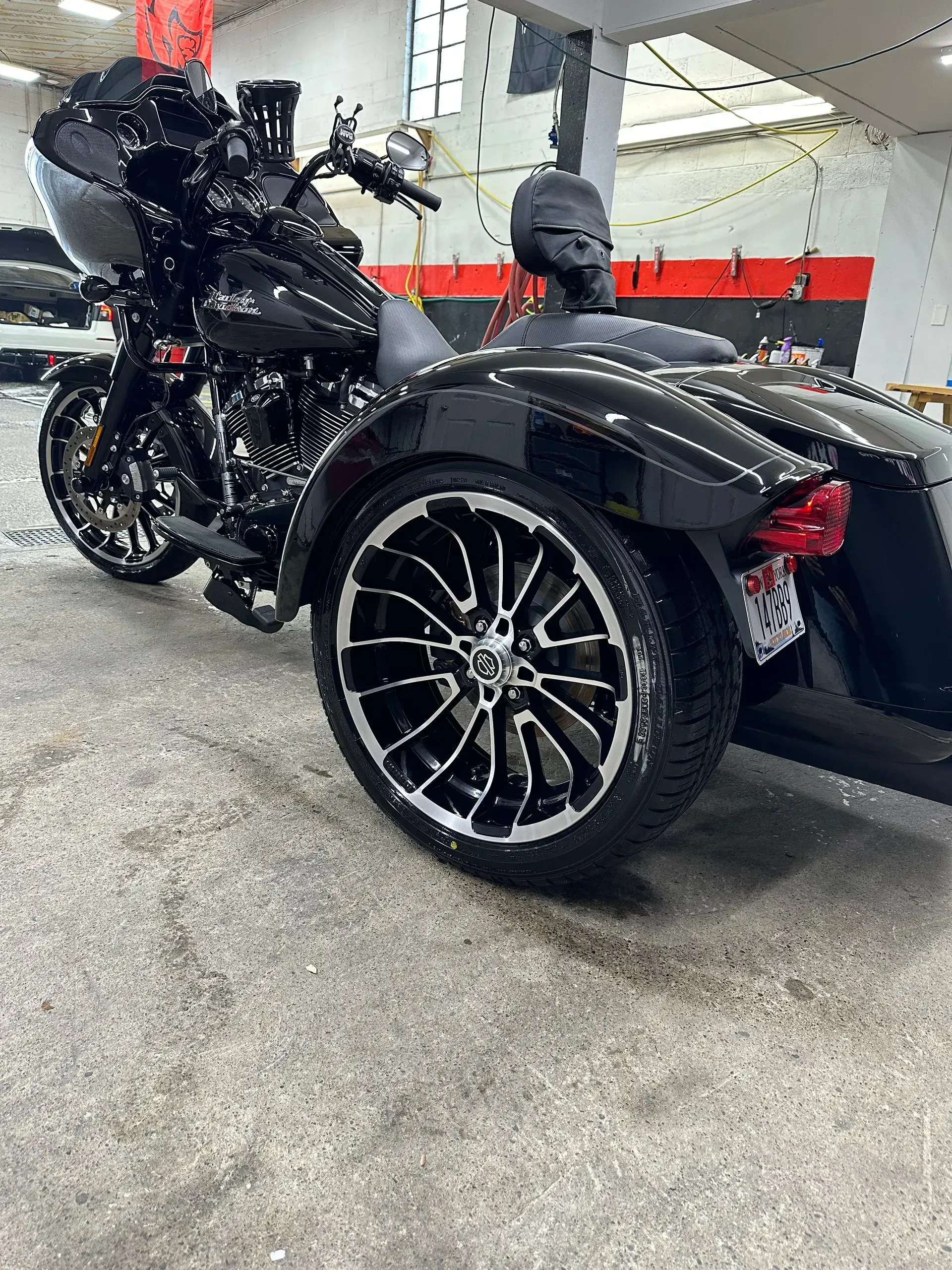 Black Harley-Davidson trike motorcycle with black and silver wheels parked indoors.