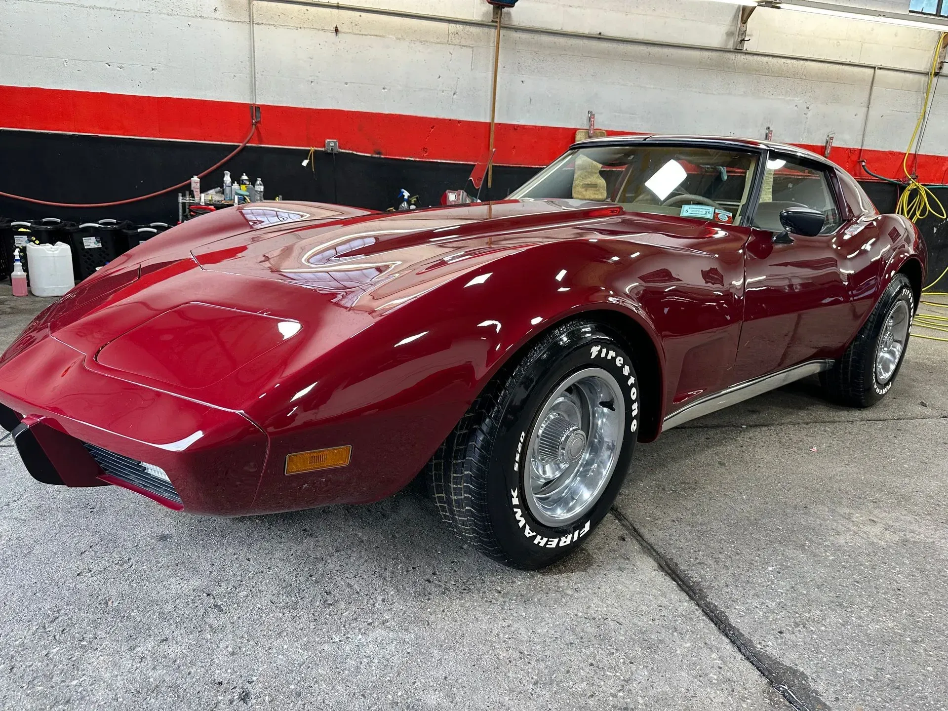 Maroon classic Corvette sports car parked indoors, showing off its shiny finish.