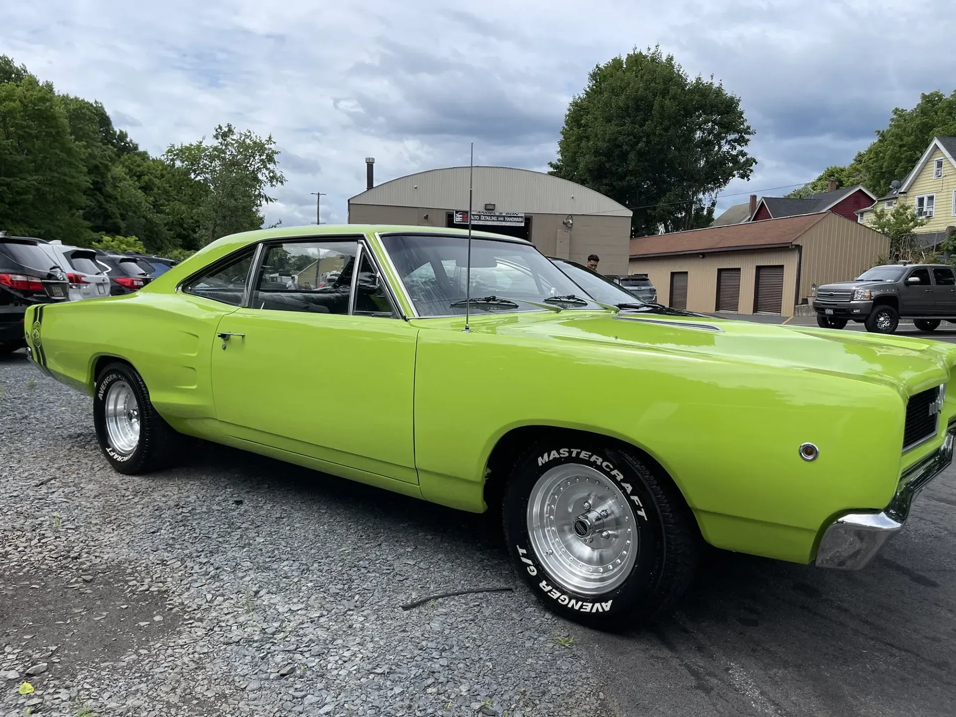Bright green 1968 Dodge Coronet R/T muscle car parked on asphalt with silver wheels. Overcast day.
