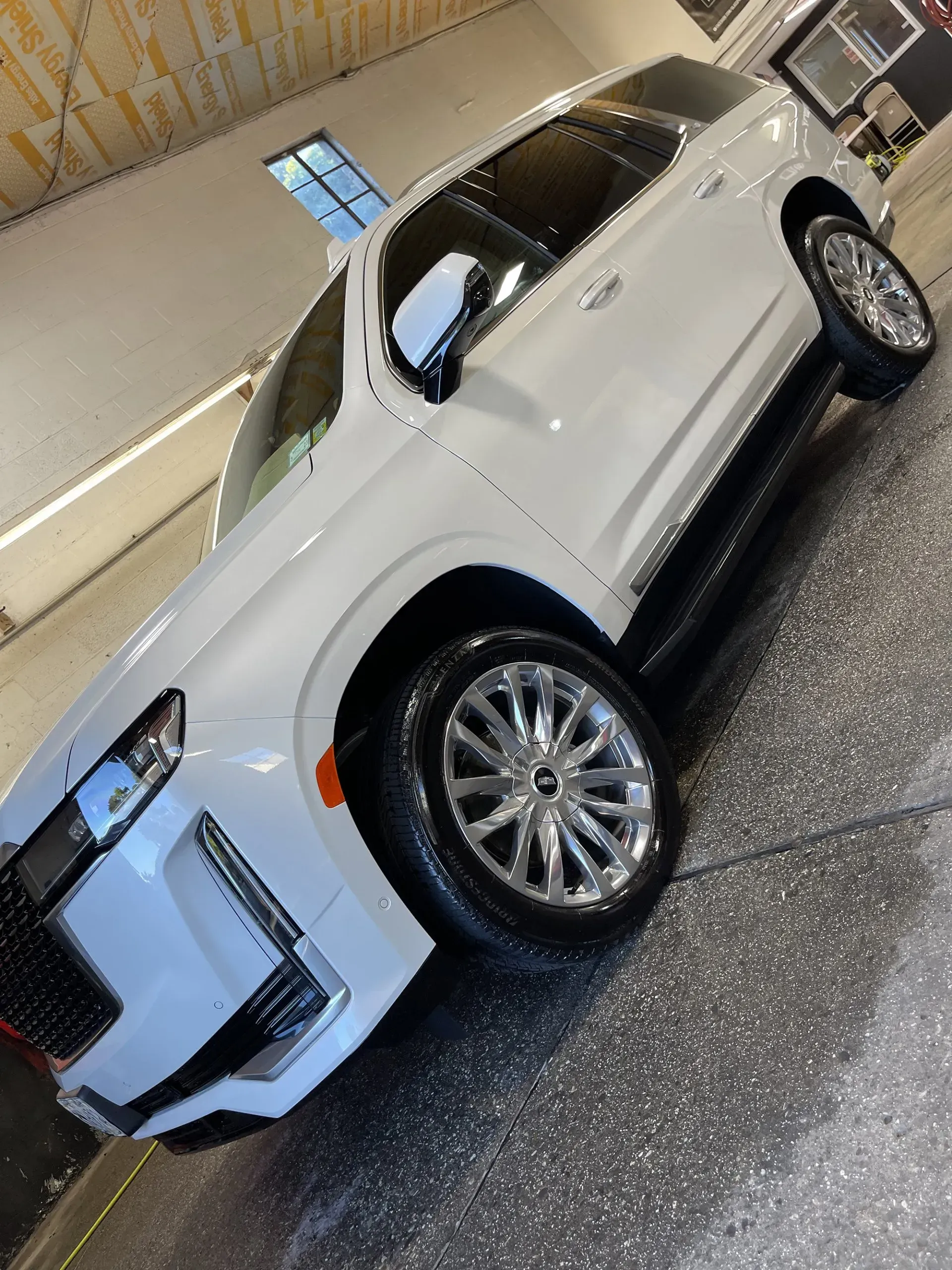 White SUV with chrome wheels parked inside a car wash, angled view.