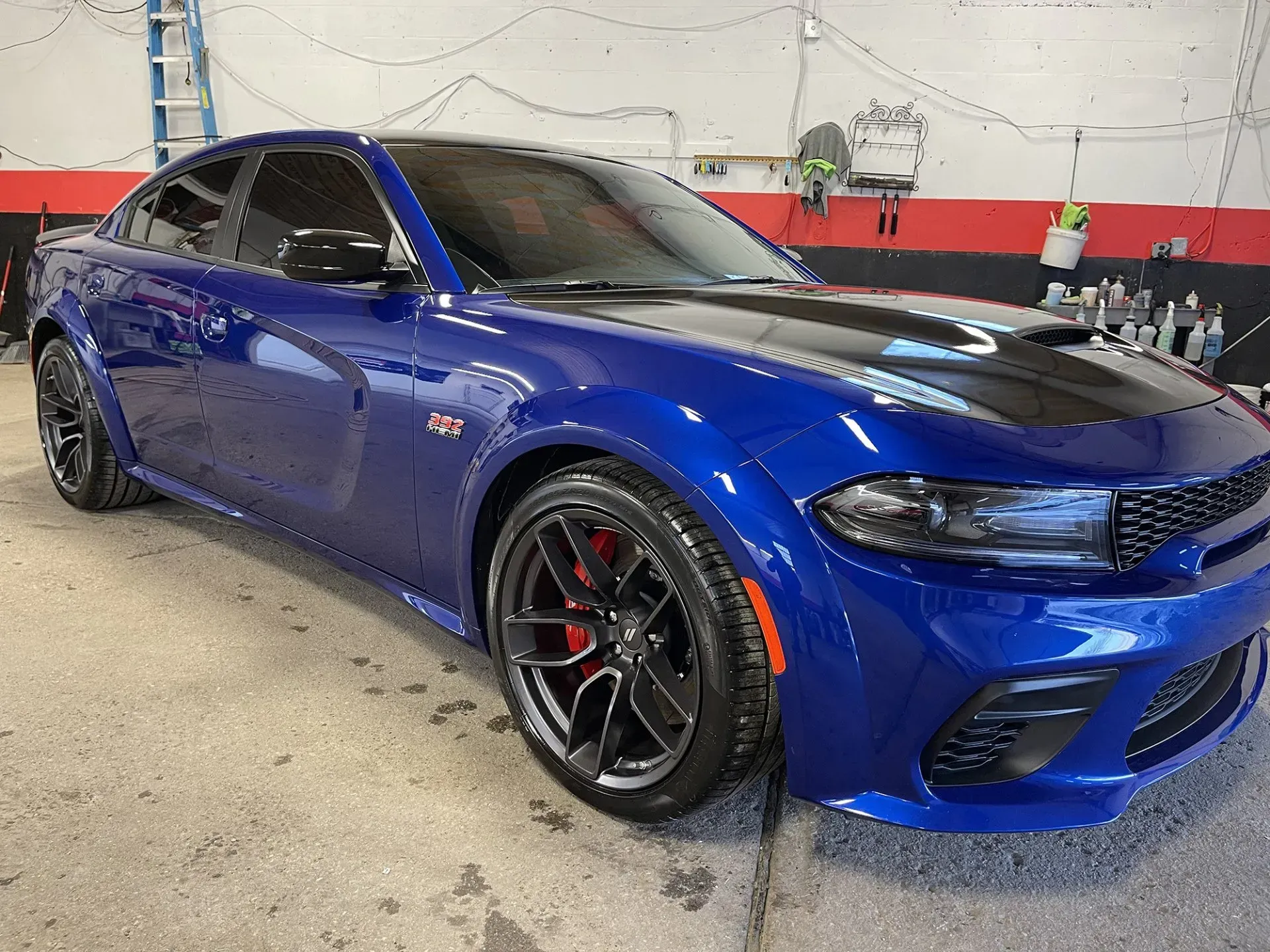 Blue Dodge Charger with black hood, red brake calipers, and tinted windows, parked indoors.