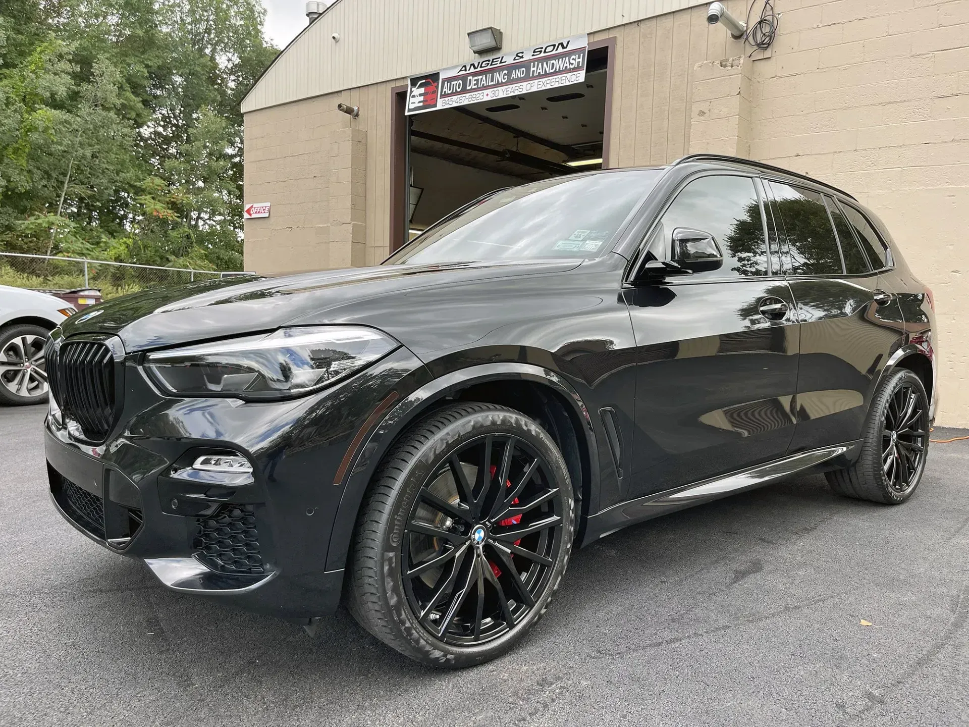 Black BMW SUV parked in front of a building with its garage door open.