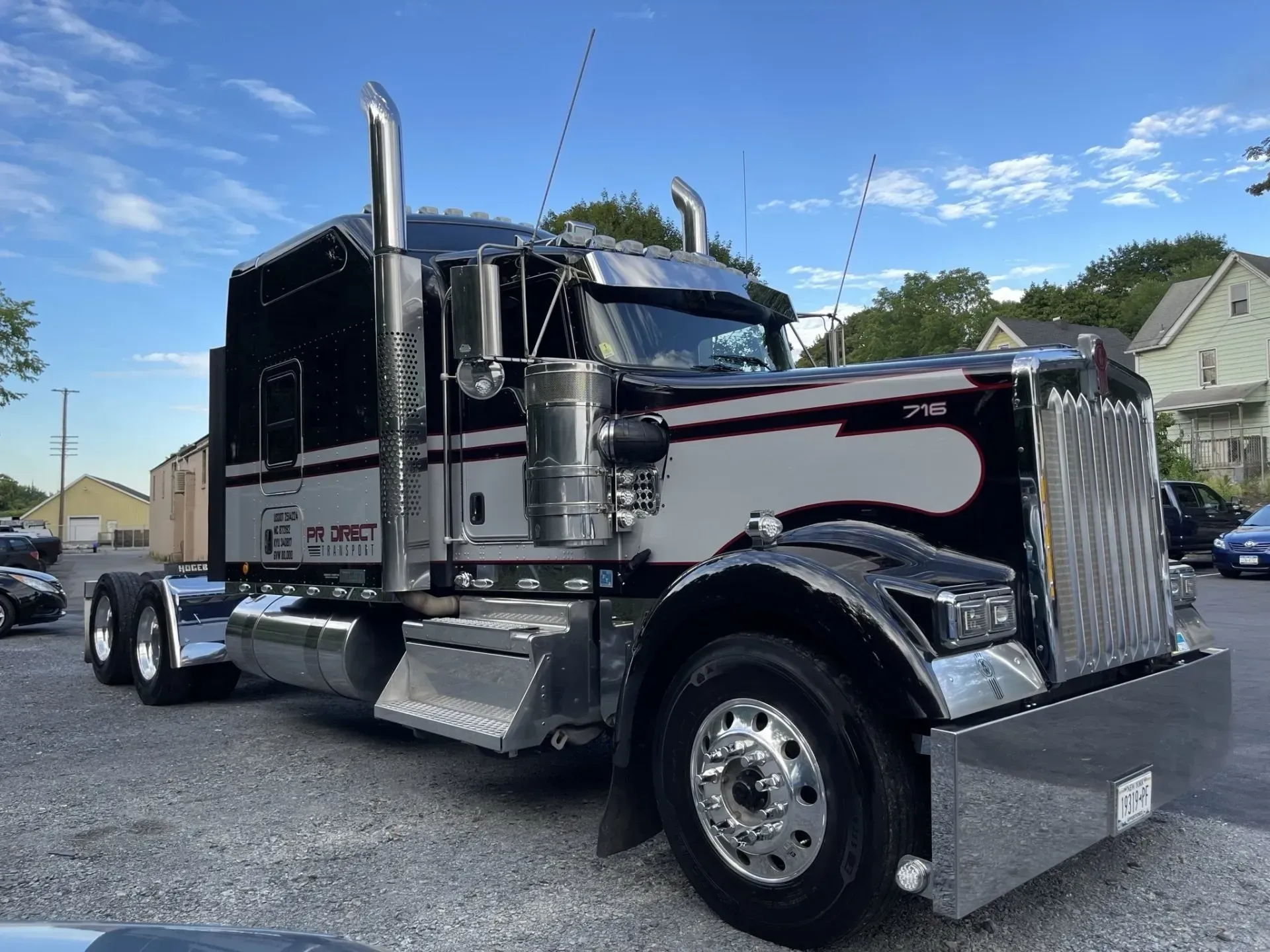 Black and silver semi-truck parked outside, sunny day. Chrome detailing and large exhaust stacks.