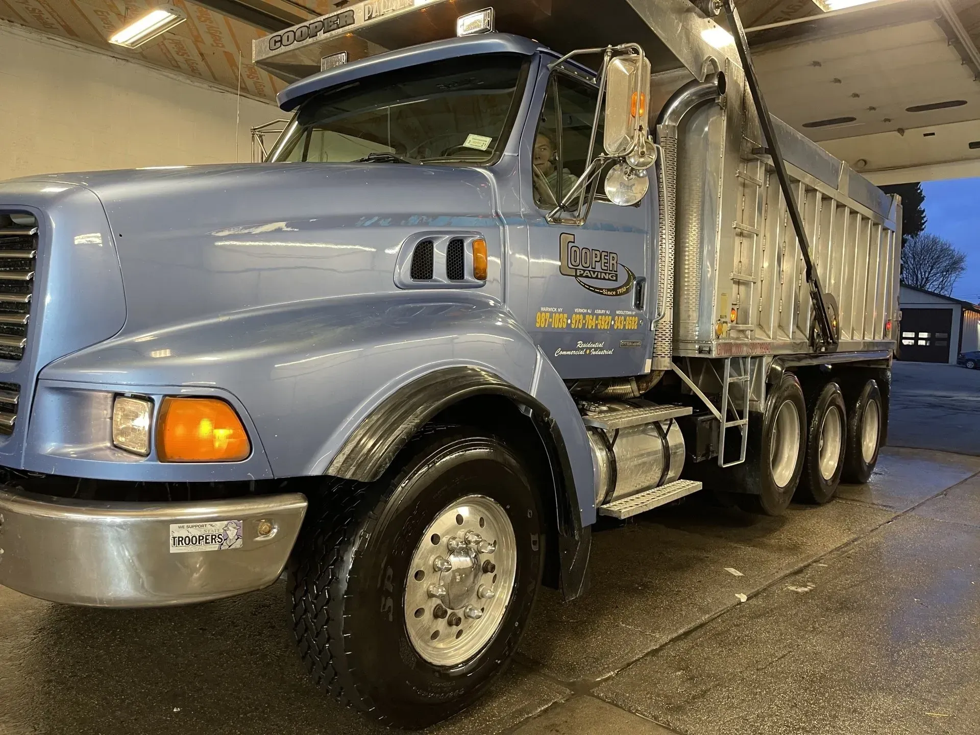 Blue dump truck in a wash bay.